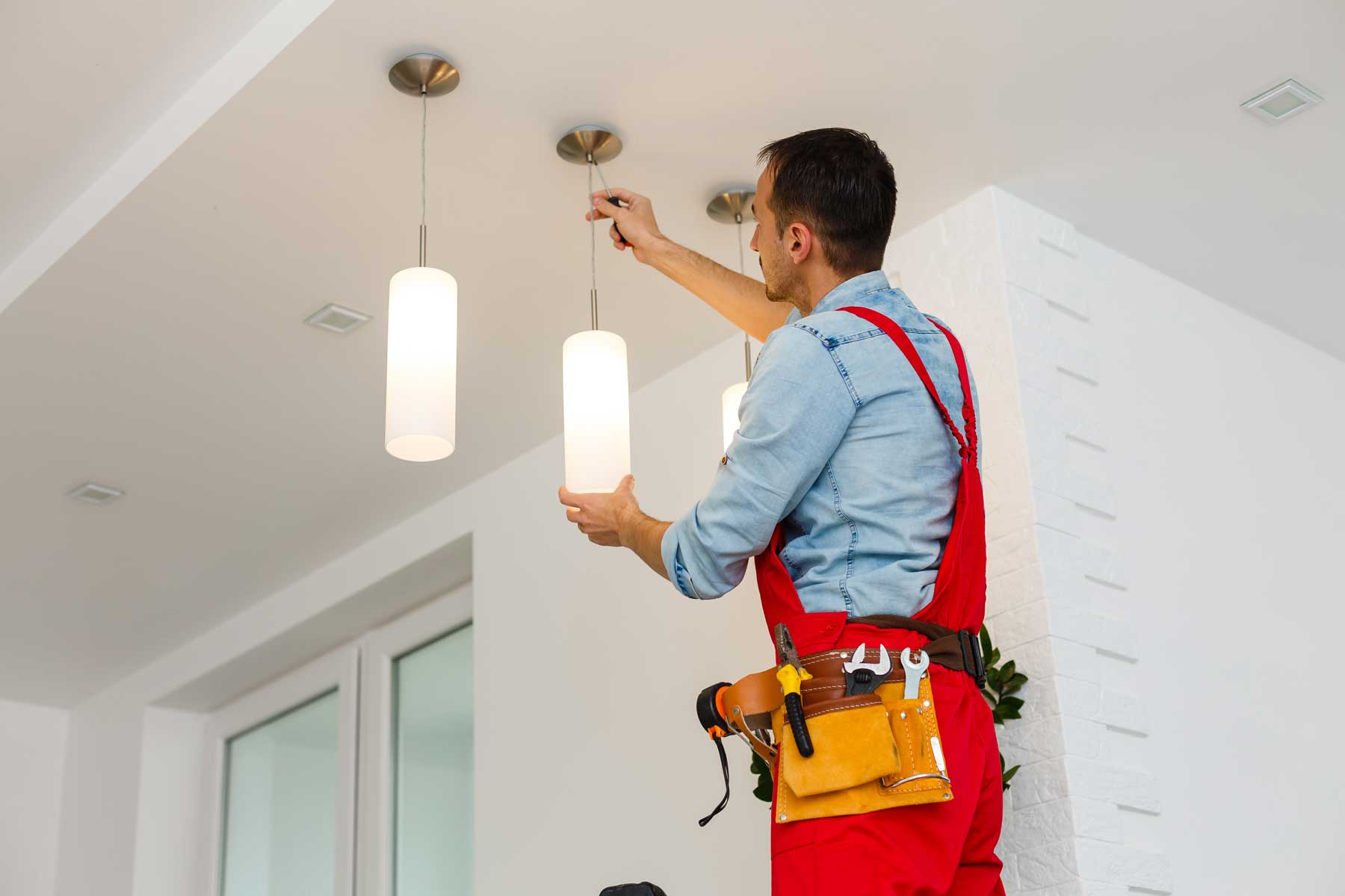 Homeguide Electrician Installing Pendant Light Fixtures Electrician Technician At Work With Safety Equipment On A Residential Electrical System
